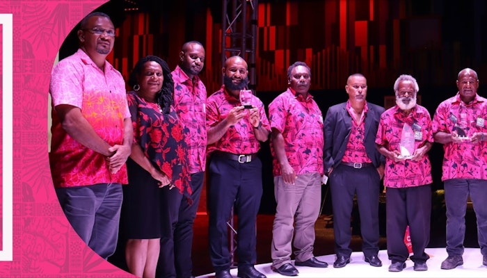 A group of men wearing pink shirts receiving awards